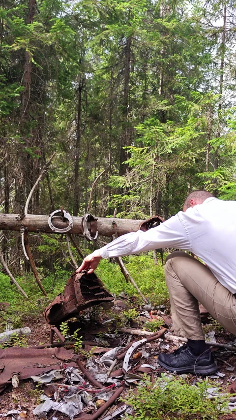 Man examining rusted plane crash wreckage on mountain forest slope Vídeo Stock 344877340