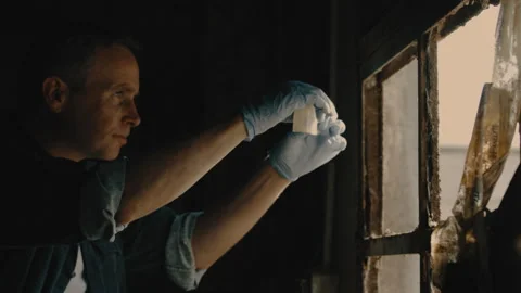 Man examining tape in front of window in sunlight Stock Footage 275705402