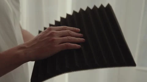 Man examining texture of acoustic foam panel, considering soundproofing Stock Footage 305504516