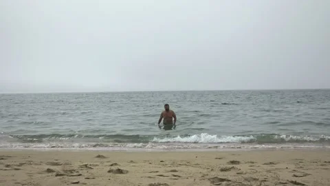 A man with excess weight and a large stomach comes out of the ocean after Stock Footage 230277167