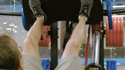A man with excess weight doing leg presses on the simulator in the gym. Fitness Video stock 111887686