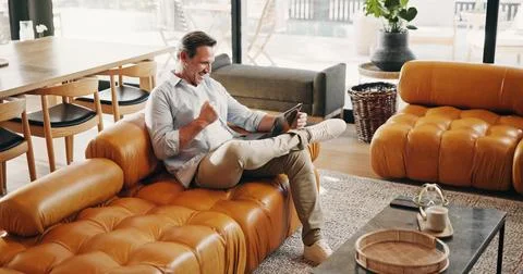 Man, excited and tablet on sofa with fist pump, good news and streaming spo.. Stock Photos