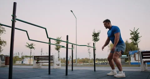 A man is executing a series of squats at an outdoor gym that features parallel Video stock 317981029