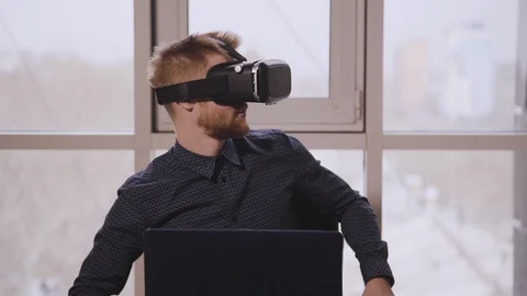 Man executive using virtual reality headset sitting at desk with laptop in Stock Footage 119454761