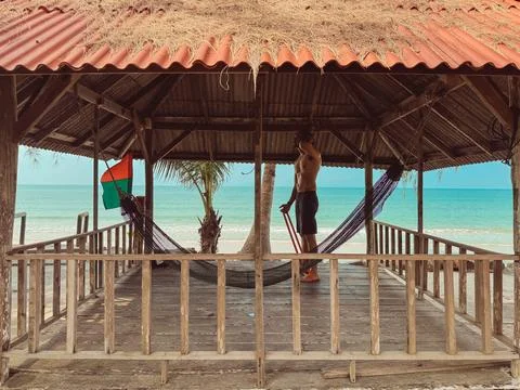 Man exercise and workout with rubber band in the hut by the sea. Beach rela.. Фото