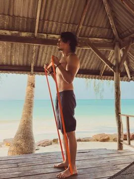 Man exercise and workout with rubber band in the hut by the sea. Beach rela.. Foto stock