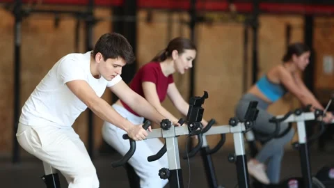 Man on an exercise bike during a group workout to the gym. European in a Stock Footage 320001819