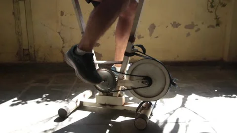 A man exercise on a old, vintage, precarious static bicycle on a low income hous Stock Footage 139425253