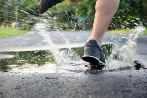 Man exercise running through puddle splashing his shoes. Stock Photos
