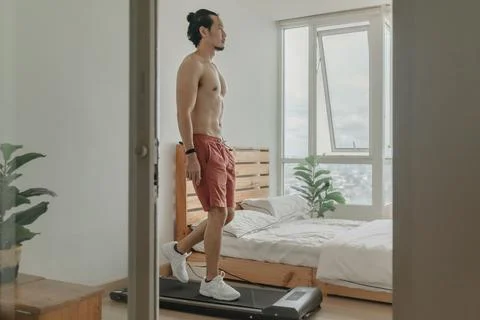 Man exercise by walking on the treadmill in his apartment. Fotos de archivo