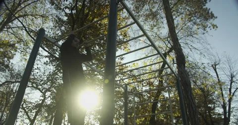 Man exerciser workout on bars, pull ups exercise, park autumn scene in sunset Stock Footage 143902983