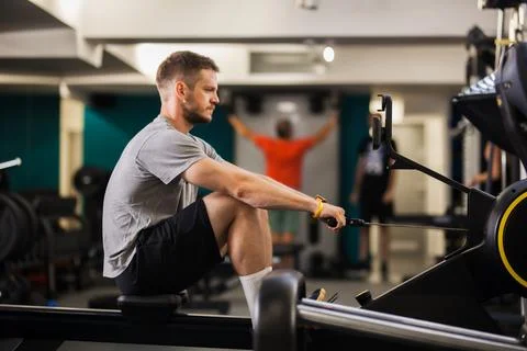Man exercises on rowing machine in gym on a weekday morning with others in the Photos