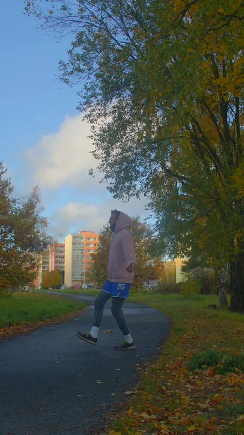 Man exercises vigorously alongside cityscape and colorful trees Stock Footage 324592709