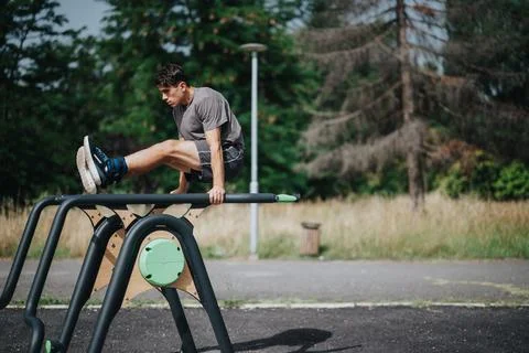 Man exercising abs on parallel bars in a park during a workout session Stock-Fotos