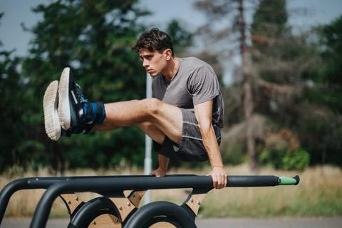 Man exercising abs on parallel bars in the park on a sunny day Stock-Fotos