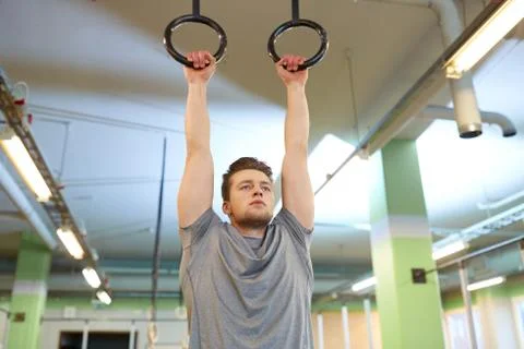 Man exercising and doing ring pull-ups in gym Stock Photos