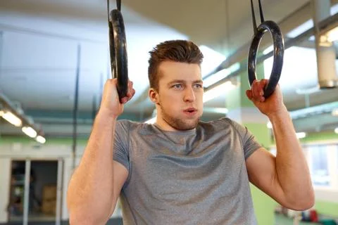 Man exercising and doing ring pull-ups in gym Stock Photos