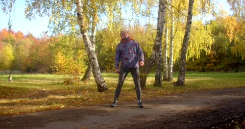 Man exercising on birch-lined park path during sunny autumn day in CZ Stock Footage 348877953
