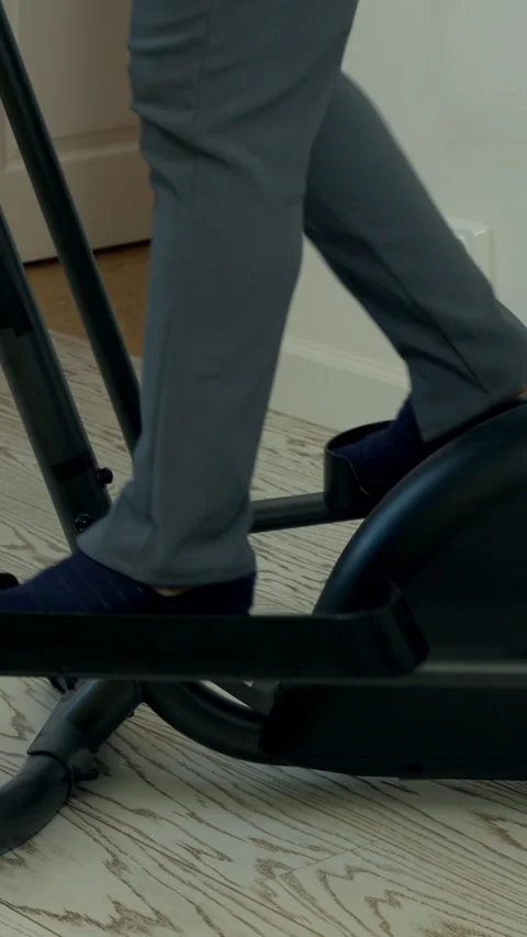 Man exercising on elliptical trainer at home Stock Footage 327364680