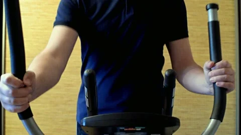 A man exercising on elliptical trainer machine Stock Footage 143457243
