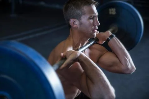 Man exercising in gym, using barbell, front squat position Stock Photos