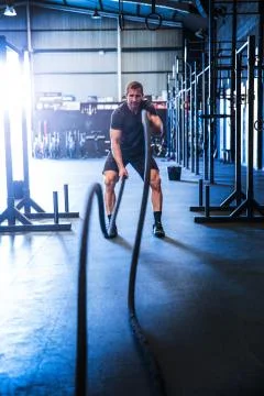 Man exercising in gym, using battle ropes Stock Photos