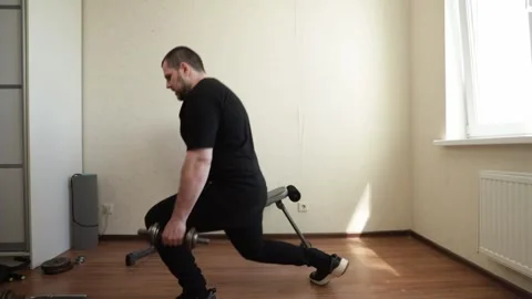 Man exercising in home gym, practicing strength training with dumbbells, en.. Stock Footage 283902792
