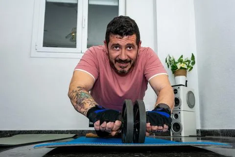 Man exercising at home using ab roller wheel 库存照片