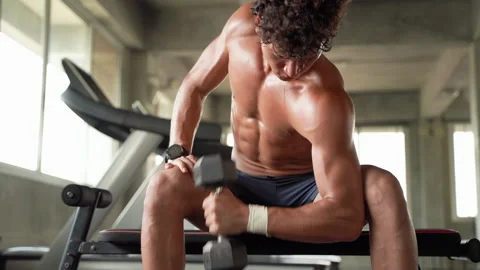 A man is exercising by lifting a dumbbell inside the gym. Stock Footage 141288181