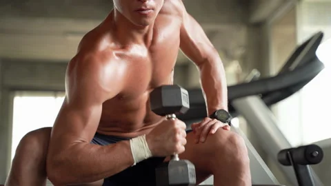 A man is exercising by lifting a dumbbell inside the gym. Stock Footage 141288991