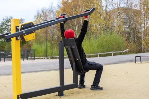A man is exercising on an outdoor lat pulldown machine in a public place in F Foto stock