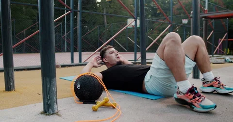 A man is exercising outdoors, doing crunches to improve his health and wellbeing Stock Footage 317977586