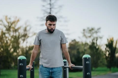 Man exercising outdoors on parallel bars in a peaceful park setting 스톡 사진