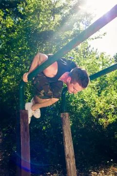 Man exercising on parallel bars outdoors Stock Photos
