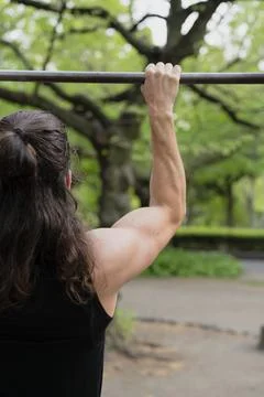 Man exercising on pull-up bar in outdoor park setting Stock Photos