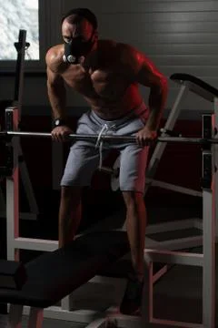 Man Exercising Push-Ups On Barbell In Elevation Mask Stock Photos