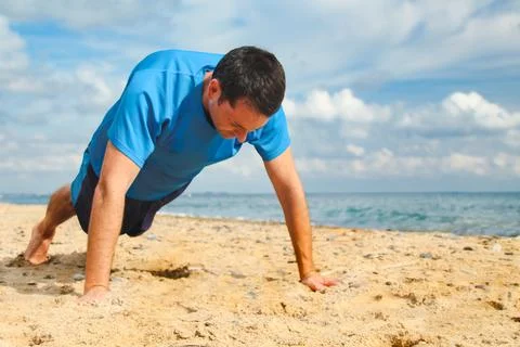 Man Exercising with Push-Ups on Beach Stock Photos