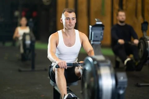 Man exercising on rowing machine during high intensity workout Photos