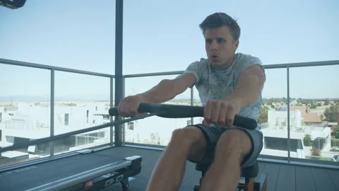 Man exercising with a rowing machine on a rooftop Video stock 170885309