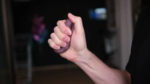 A man exercising with a rubber expander on a blurry dark background of the room  Stock Footage 146829823