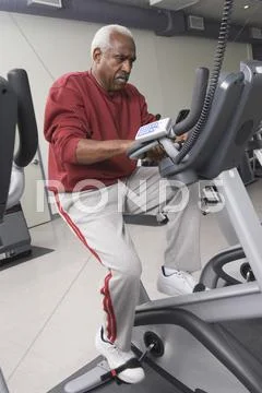 Man Exercising On Stationary Bike In Health Club Stock Photos