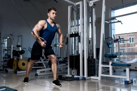 Man is exercising on a training machine in the gym Stock Photos