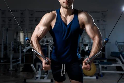 Man is exercising on a training machine in the gym close-up Stock Photos