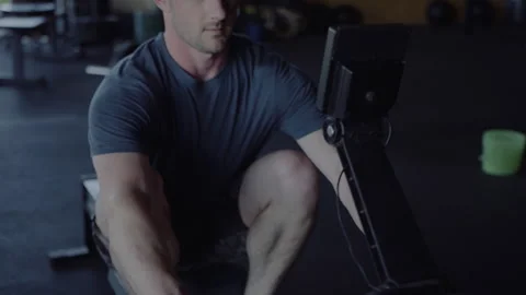 Man exercising vigorously on rowing machine in small gym space Stock Footage 312703773