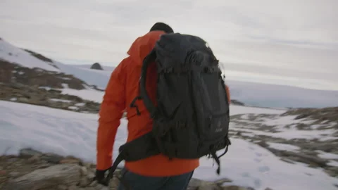 Man exits cabin with backpack ready for hiking adventure in scenic landscape Stock Footage 288193926