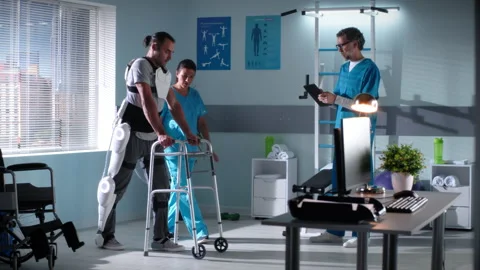 Man with exoskeleton and walking frame having rehabilitation session with Stock Footage 156688160