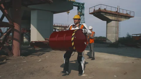 Man in exoskeleton carrying barrel on construction site Stock Footage 159393583