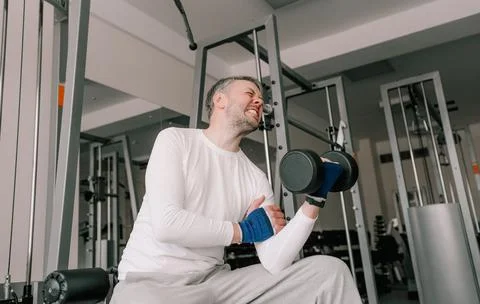 A man experiences pain while exercising his biceps in the gym. intensive spor Foto stock