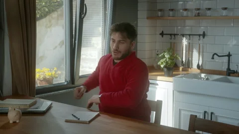 Man Experiencing Back Pain While Sitting in a Cozy Kitchen Stock Footage 303662912