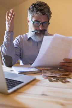 Man experiencing financial problems reading bills and calculating expenses 스톡 사진